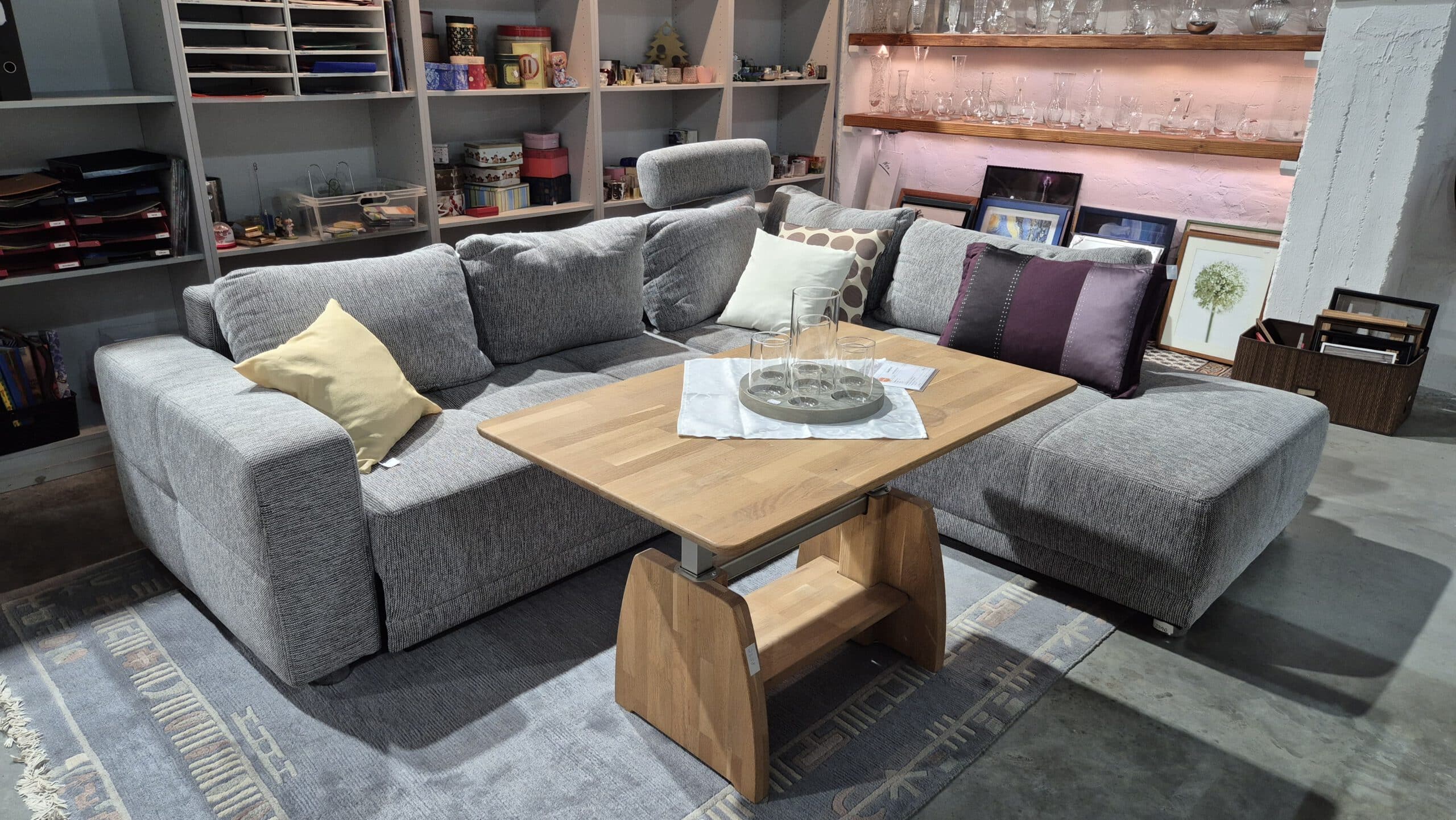 graue Eckcouch mit höhenverstellbarem Wohnzimmertisch